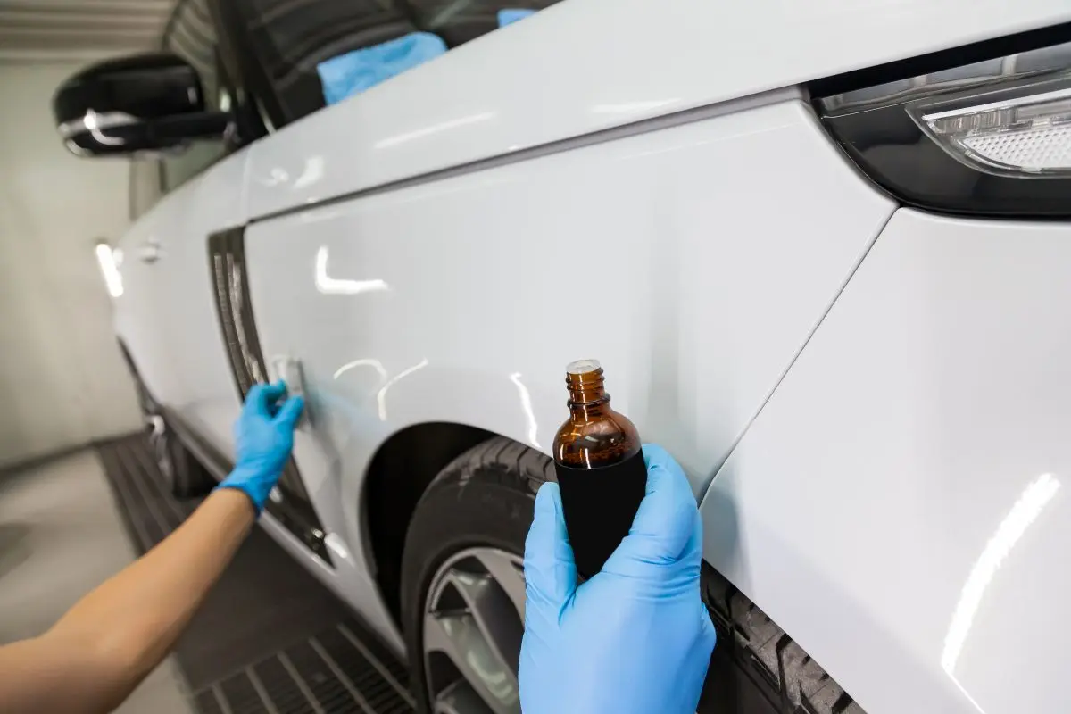 process applying nanoceramic coating white car s fender by male worker with sponge bottle chemical composition hand protect paint detailing workshop